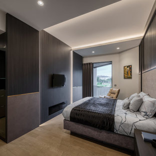 Diseño de dormitorio principal, actual, de tamaño medio, con paredes grises, chimenea lineal, marco de chimenea de madera y suelo beige