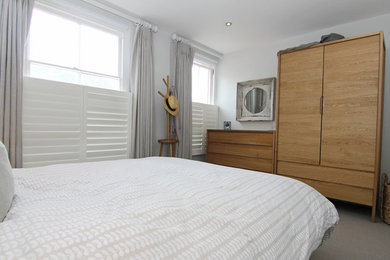 Ejemplo de dormitorio principal costero pequeño sin chimenea con paredes blancas y moqueta