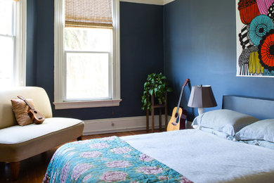 This is an example of an eclectic bedroom in San Francisco with blue walls, medium hardwood flooring and orange floors.