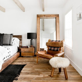 Modelo de habitación de invitados de estilo de casa de campo, grande, con paredes blancas, suelo de madera clara y suelo marrón