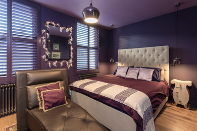 Design ideas for a medium sized bohemian master bedroom in London with purple walls and medium hardwood flooring.