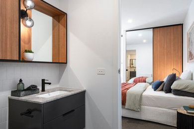 メルボルンにある広いコンテンポラリースタイルのおしゃれな客用寝室 (白い壁、カーペット敷き、グレーの床)