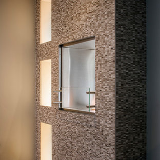 Imagen de dormitorio principal, contemporáneo, pequeño, con paredes grises, suelo de madera clara, chimenea de doble cara, marco de chimenea de piedra y suelo marrón
