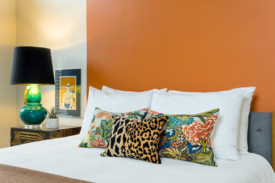 Immagine di una grande camera degli ospiti etnica con pareti arancioni e pavimento in legno massello medio