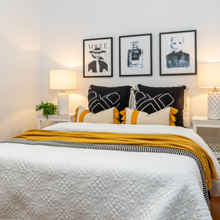 Contemporary bedroom in Brisbane with white walls, medium hardwood floors and brown floor.