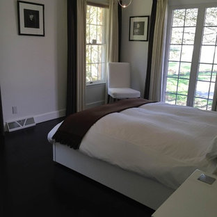 Modelo de dormitorio principal, actual, de tamaño medio, con paredes blancas, suelo de madera oscura y suelo negro