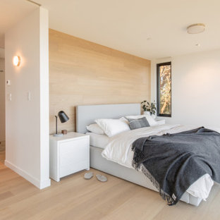 Idee per una camera da letto design con pareti beige, parquet chiaro, pavimento beige e pareti in legno