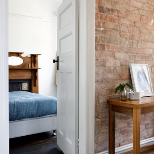 Imagen de habitación de invitados contemporánea con paredes blancas, suelo de madera pintada, chimenea tradicional, marco de chimenea de madera y suelo negro