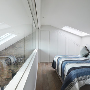 Photo of a small contemporary mezzanine bedroom in London with white walls, light hardwood flooring and no fireplace.