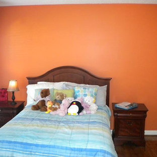 Ejemplo de habitación de invitados clásica, pequeña, sin chimenea, con parades naranjas y suelo de madera oscura
