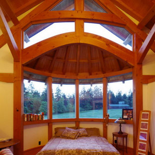 Modelo de dormitorio principal, grande, con paredes blancas, suelo de madera en tonos medios, chimenea de esquina y marco de chimenea de madera
