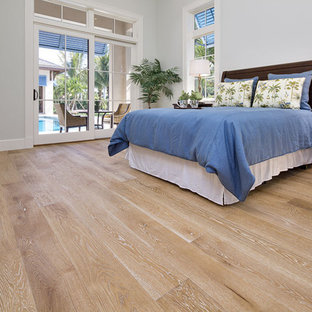Modelo de dormitorio principal, tropical, grande, con paredes grises y suelo de madera clara