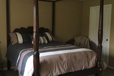 グランドラピッズにある中くらいなトラディショナルスタイルのおしゃれな客用寝室 (茶色い壁、カーペット敷き、暖炉なし)