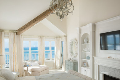 ロサンゼルスにあるビーチスタイルのおしゃれな主寝室 (白い壁、カーペット敷き、標準型暖炉、石材の暖炉まわり) のインテリア