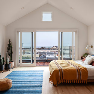 Imagen de dormitorio principal, moderno, con paredes blancas, suelo de madera clara, estufa de leña y marco de chimenea de metal
