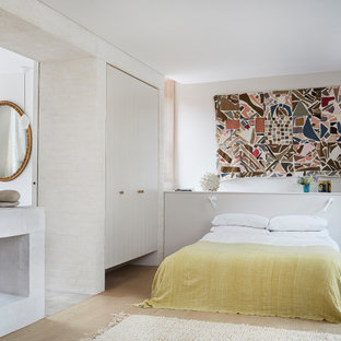 Photo of a medium sized contemporary master bedroom in London with white walls, beige floors, light hardwood flooring, a two-sided fireplace and a brick fireplace surround.