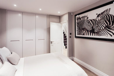 Photo of a medium sized master bedroom in London with white walls, laminate floors and brown floors.
