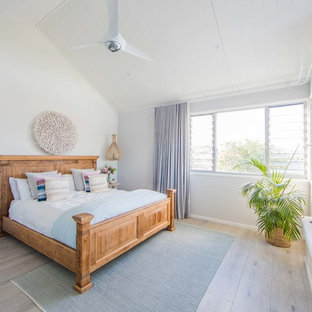 Design ideas for a large beach style master bedroom in Gold Coast - Tweed with white walls, light hardwood floors and grey floor.
