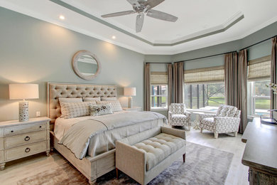 This is an example of a large classic master bedroom in Orlando with green walls, light hardwood flooring and no fireplace.