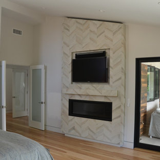 Idee per una camera matrimoniale design con pareti beige, parquet chiaro, camino classico, cornice del camino piastrellata e pavimento giallo