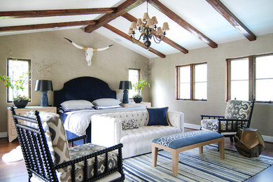Cette photo montre une grande chambre parentale méditerranéenne avec un mur beige et un sol en bois brun.