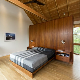 Imagen de dormitorio principal, minimalista, de tamaño medio, sin chimenea, con paredes blancas, suelo de madera clara y suelo beige