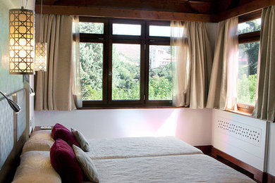 マドリードにある中くらいな地中海スタイルのおしゃれな客用寝室 (白い壁、濃色無垢フローリング、暖炉なし)