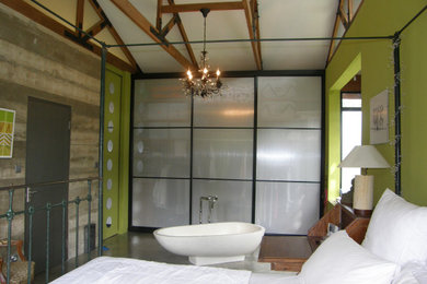 Diseño de dormitorio principal tropical de tamaño medio sin chimenea con paredes verdes, suelo de cemento y suelo gris