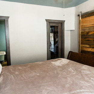 Imagen de dormitorio principal, rústico, pequeño, con paredes blancas, moqueta, estufa de leña, marco de chimenea de piedra y suelo marrón