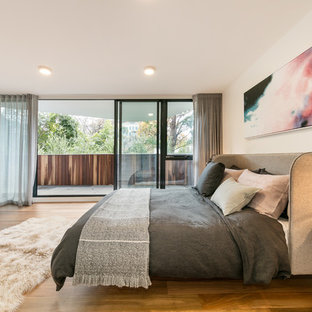 Contemporary master bedroom in Melbourne with white walls, medium hardwood floors and brown floor.
