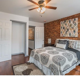 Diseño de dormitorio urbano con paredes blancas, suelo de madera en tonos medios y suelo marrón
