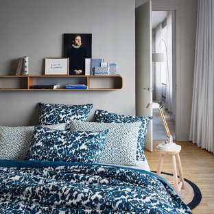 Cette photo montre une petit chambre parentale scandinave avec un sol en bois clair et un mur gris.
