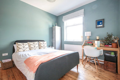Mittelgroßes Modernes Schlafzimmer mit blauer Wandfarbe, hellem Holzboden und braunem Boden in London