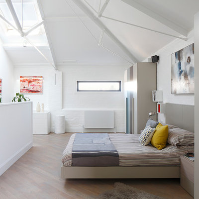 Example of a mid-sized trendy master light wood floor and beige floor bedroom design in London with white walls