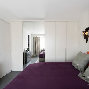 Contemporary bedroom in London with white walls, dark hardwood flooring and black floors.