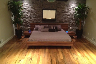 Modelo de dormitorio principal minimalista extra grande con paredes grises y suelo de madera en tonos medios