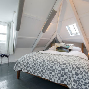 Photo of a small coastal bedroom in Cornwall with white walls, painted wood flooring, black floors and a vaulted ceiling.