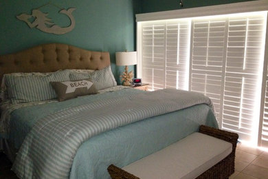 Ejemplo de dormitorio principal costero de tamaño medio sin chimenea con paredes verdes, suelo de baldosas de cerámica y suelo beige