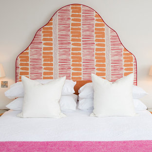 This is an example of a coastal bedroom in London with beige walls and no fireplace.