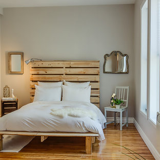 Imagen de dormitorio ecléctico, pequeño, sin chimenea, con paredes grises y suelo de madera en tonos medios