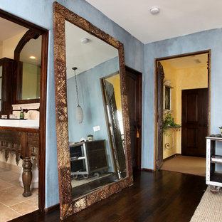 Photo of an expansive mediterranean master bedroom in Los Angeles with blue walls, dark hardwood floors, a standard fireplace, a stone fireplace surround and brown floor.