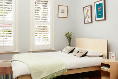 Imagen de dormitorio actual con paredes grises y suelo de madera en tonos medios