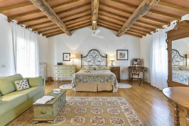 Diseño de dormitorio principal de estilo de casa de campo grande con paredes blancas y suelo de madera en tonos medios