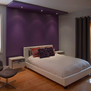 Imagen de dormitorio actual con paredes púrpuras y suelo de madera clara