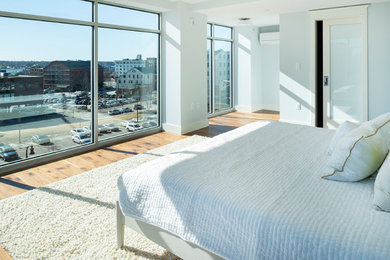 Modelo de dormitorio principal minimalista de tamaño medio con paredes azules y suelo de madera en tonos medios
