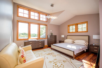 Foto de dormitorio principal actual de tamaño medio sin chimenea con paredes grises y suelo de madera en tonos medios