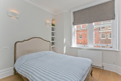 Medium sized classic master bedroom in London with white walls, laminate floors, no fireplace and brown floors.