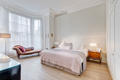 Photo of a medium sized traditional master bedroom in London with grey walls, light hardwood flooring and no fireplace.