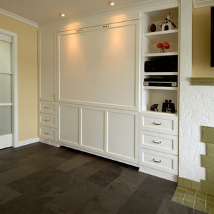 Imagen de habitación de invitados tradicional renovada, de tamaño medio, con paredes beige, suelo de pizarra, chimenea tradicional, marco de chimenea de yeso y suelo negro