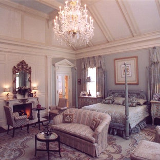 Modelo de dormitorio principal, clásico, grande, con paredes azules, suelo de madera oscura, chimenea tradicional, marco de chimenea de piedra y suelo beige